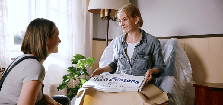 Woman handing a woman package.